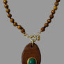 Necklace with wooden pendant and beads on a mannequin bust.