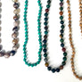 Five beaded necklaces of different colors and designs on a white background