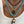 Necklace with turquoise beads and fish pendant on a white tank top