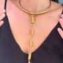 Gold necklace with a unique design worn by a person against a black background