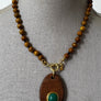 Necklace with wooden pendant and beads on a mannequin bust.